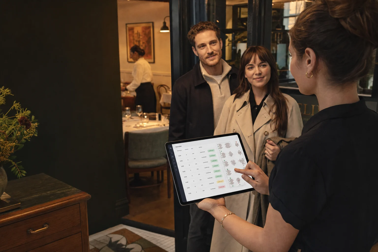 A hospitality host using a tablet while greeting guests